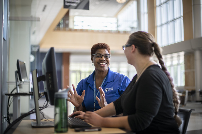 woman teaches student at a shared computer